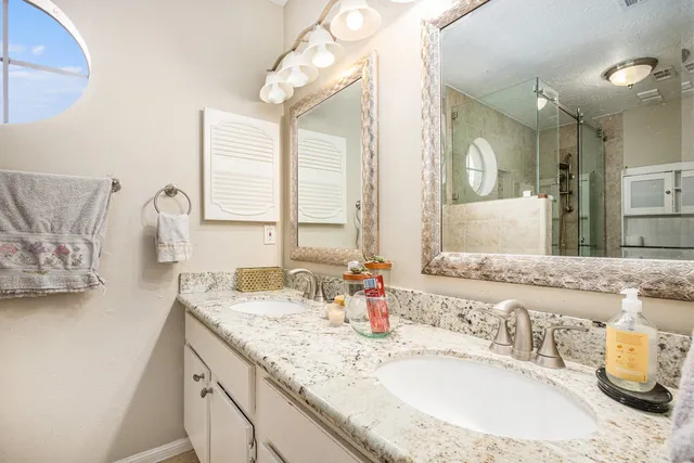 a bathroom with a granite countertop sink a large mirror and a window