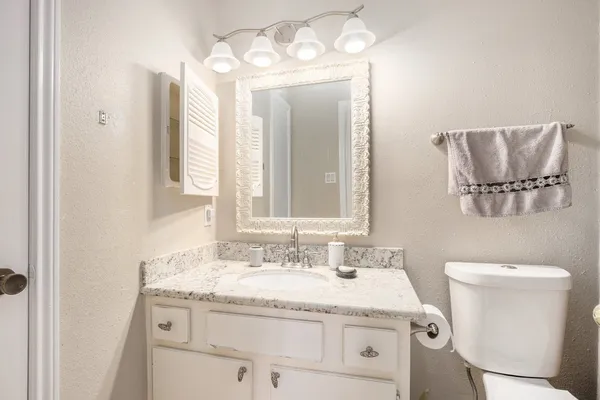 a bathroom with a granite countertop sink a toilet and a mirror