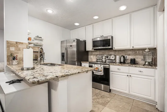 a kitchen with stainless steel appliances granite countertop a stove refrigerator sink and cabinets