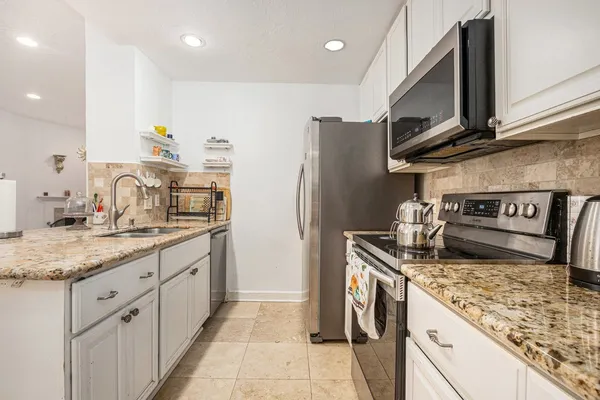 a kitchen with stainless steel appliances granite countertop a sink stove and refrigerator