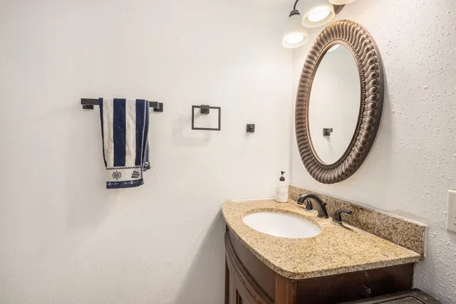 a bathroom with a granite countertop sink and a mirror