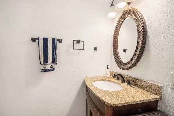 a bathroom with a granite countertop sink and a mirror