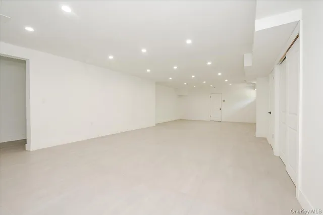 an empty room with a white wall & cabinetry