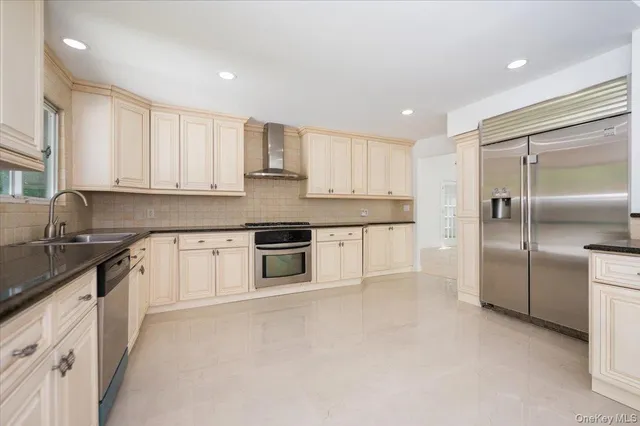 a kitchen with stainless steel appliances granite countertop white cabinets a sink a stove a refrigerator and white cabinets