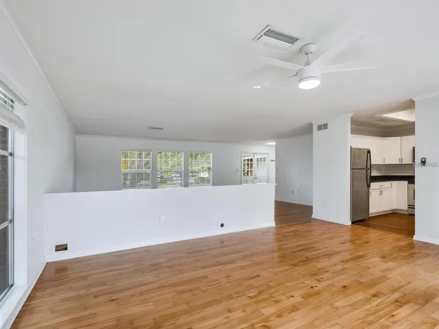 a view of empty room with wooden floor and kitchen view