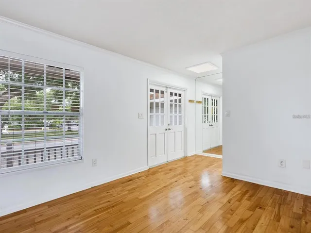 a view of an empty room with wooden floor and a window
