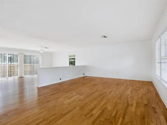 a view of empty room with wooden floor and fan