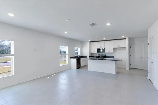 a large kitchen with kitchen island white cabinets and stainless steel appliances