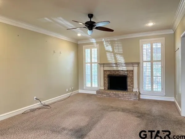 an empty room with windows fireplace and ceiling fan