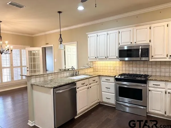 a kitchen with stainless steel appliances granite countertop a stove a sink and a microwave
