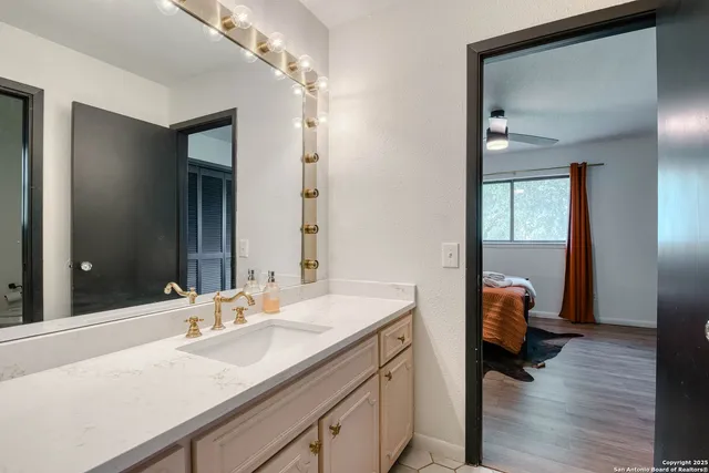 a en suite bathroom with a granite countertop sink and a mirror