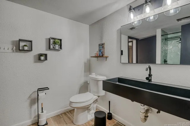 a bathroom with a sink vanity mirror and toilet