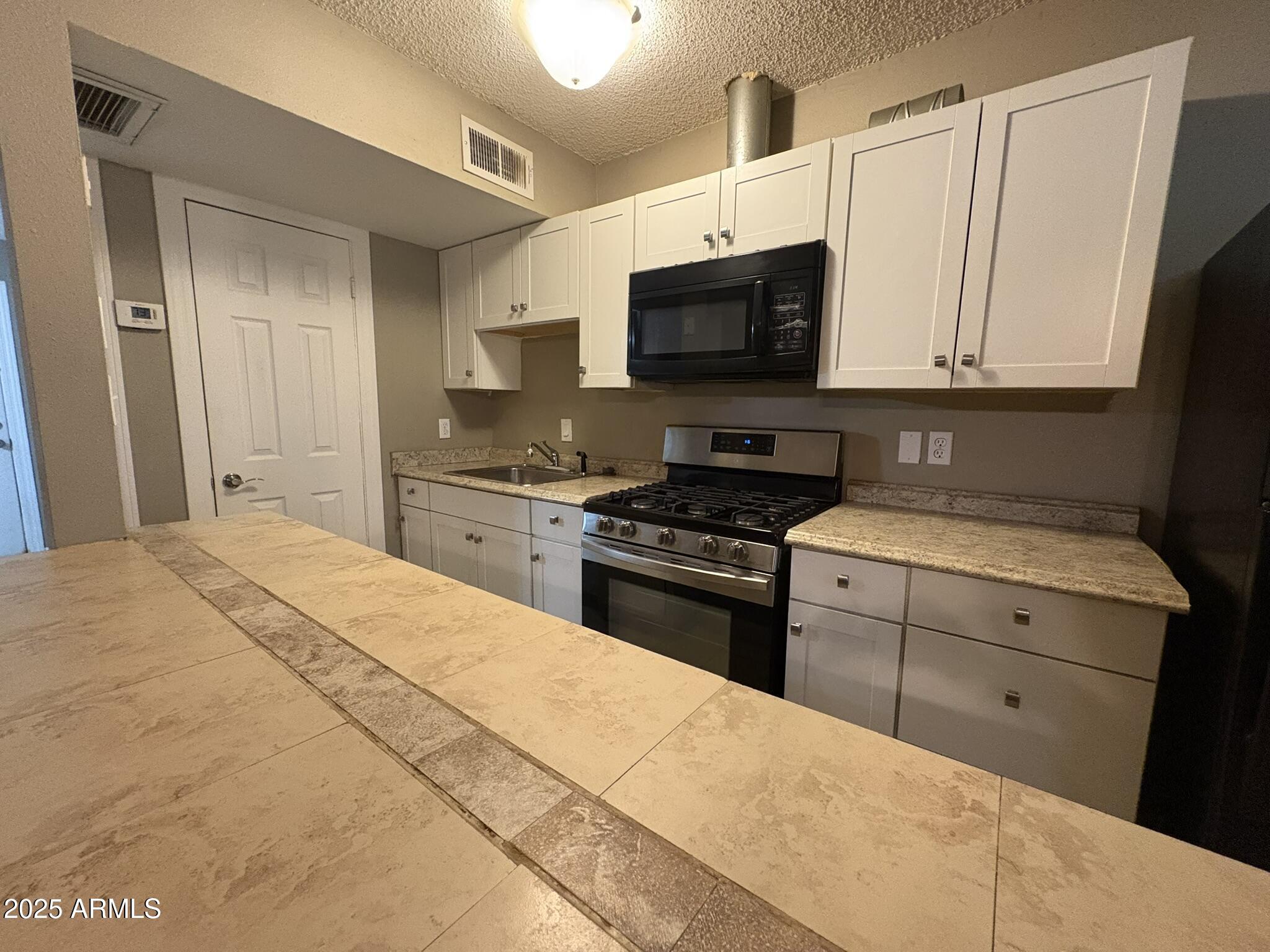 2735 West Tuckey Lane, Unit 2 Phoenix, AZ 85017 - Photo 4 of 8 a kitchen with stainless steel appliances a stove microwave and sink