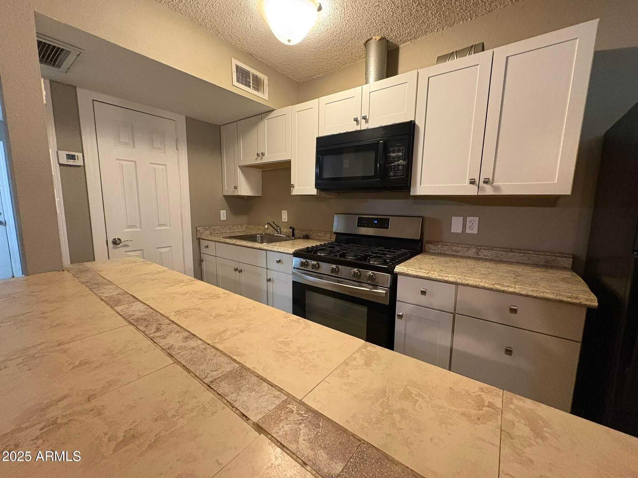 2735 West Tuckey Lane, Unit 2 Phoenix, AZ 85017 - Photo 4 of 8 a kitchen with stainless steel appliances granite countertop a stove a sink and a microwave