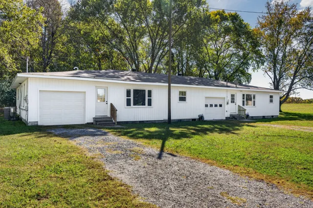 a view of a white house with a yard and a large tree