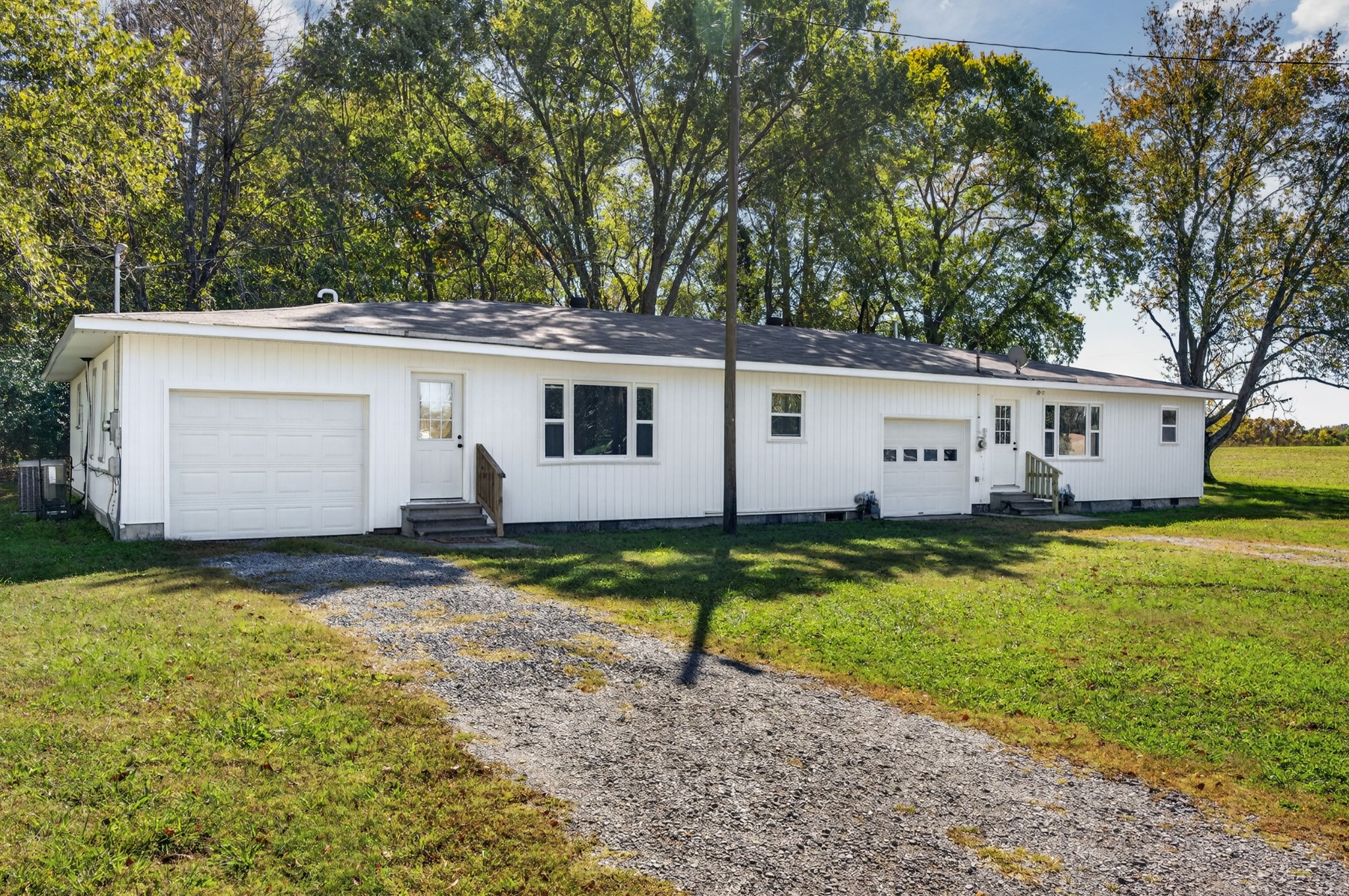 a view of a white house with a yard and a large tree