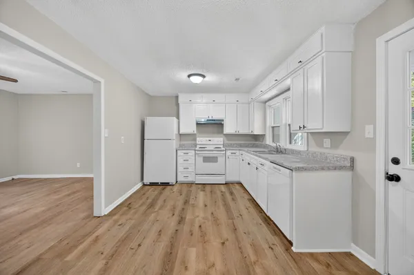 a large kitchen with cabinets wooden floor and stainless steel appliances