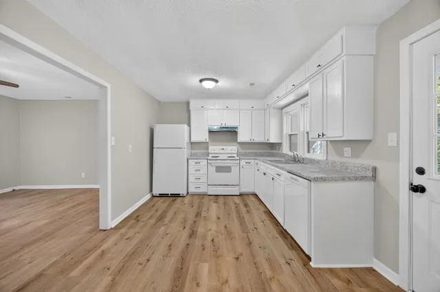 a large kitchen with cabinets wooden floor and stainless steel appliances