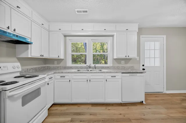 a kitchen with granite countertop white cabinets and white appliances