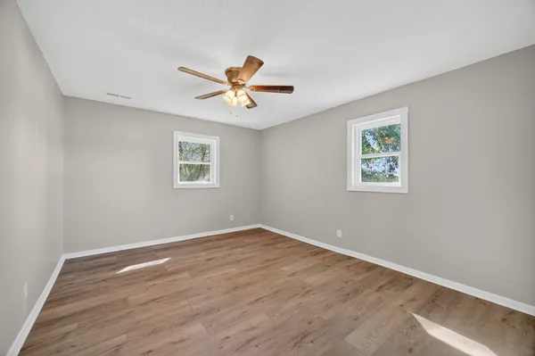 a view of a big room with wooden floor and windows