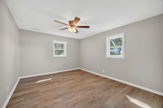 a view of a big room with wooden floor and windows