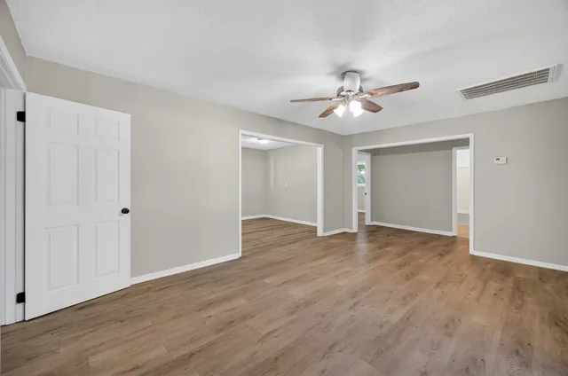 a view of a room with wooden floor and a ceiling fan