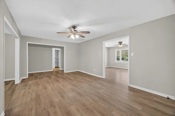 a view of an empty room with a window and wooden floor