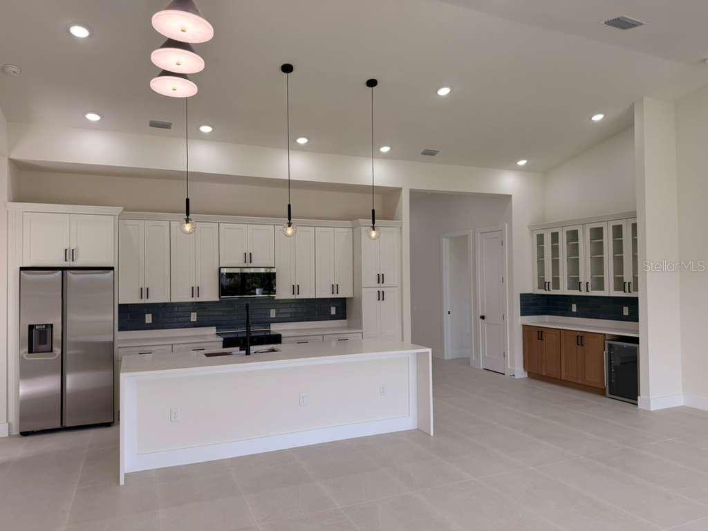 10426 Live Oak Road Port Charlotte, FL 33981 - Photo 18 of 53 a large kitchen with stainless steel appliances kitchen island granite countertop a stove a sink a refrigerator and a microwave