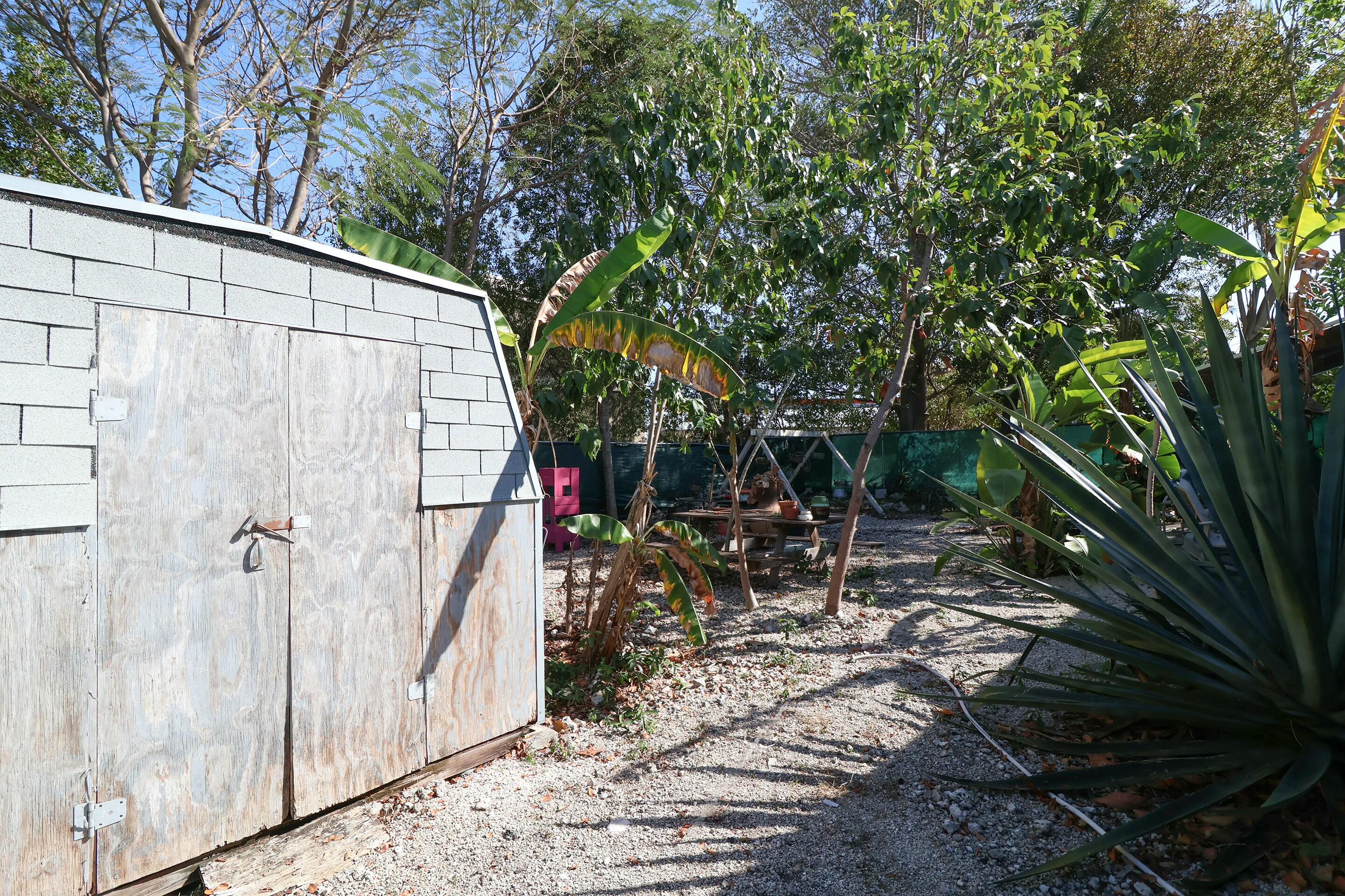 129 Lazy Lane Key Largo, FL 33037 - Photo 25 of 35 a backyard of a house with table and chairs a barbeque and a large tree