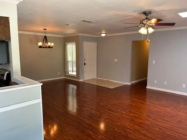 a view of an empty room with wooden floor and a ceiling fan