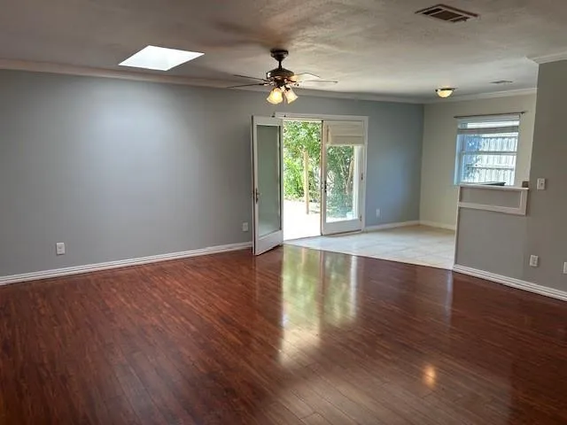 a view of an empty room with wooden floor and a window