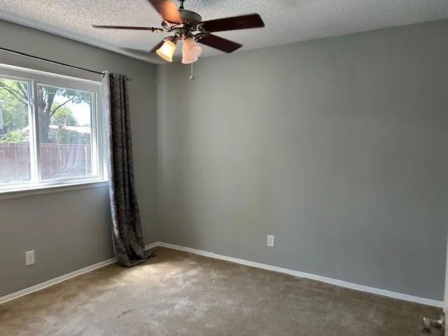 an empty room with windows and fan