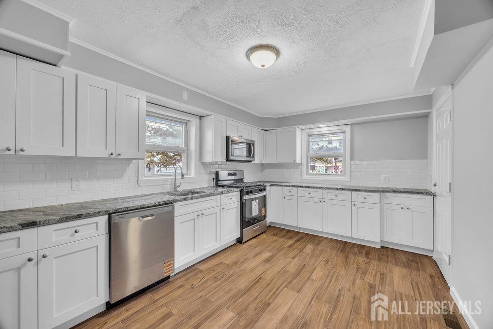 49 Comstock Street New Brunswick, NJ 08901 - Photo 2 of 20 a large kitchen with cabinets wooden floor and stainless steel appliances