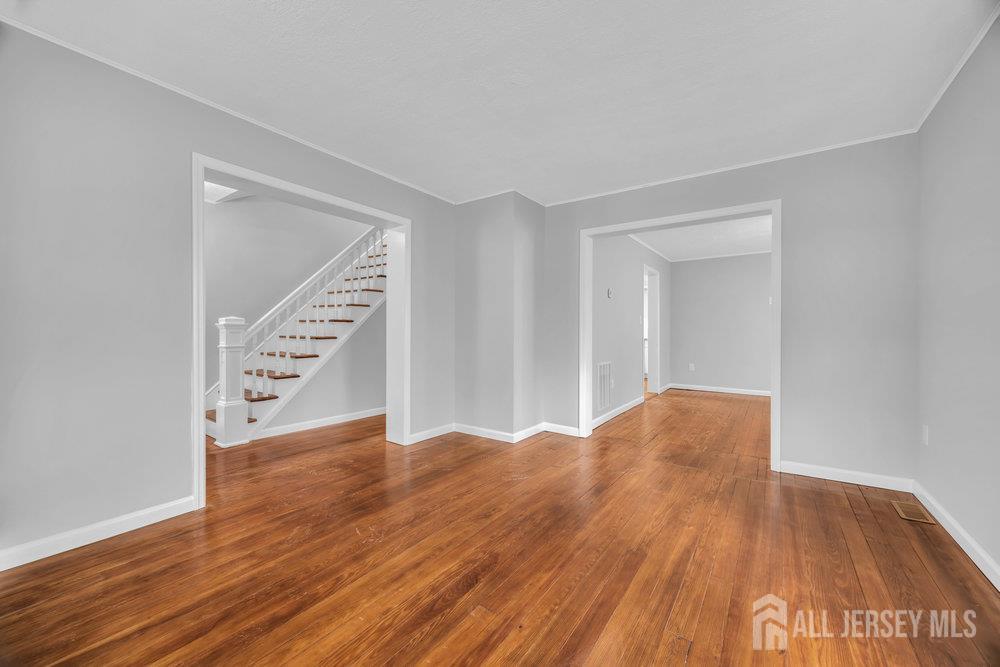 49 Comstock Street New Brunswick, NJ 08901 - Photo 5 of 20 a view of an empty room with wooden floor and stairs