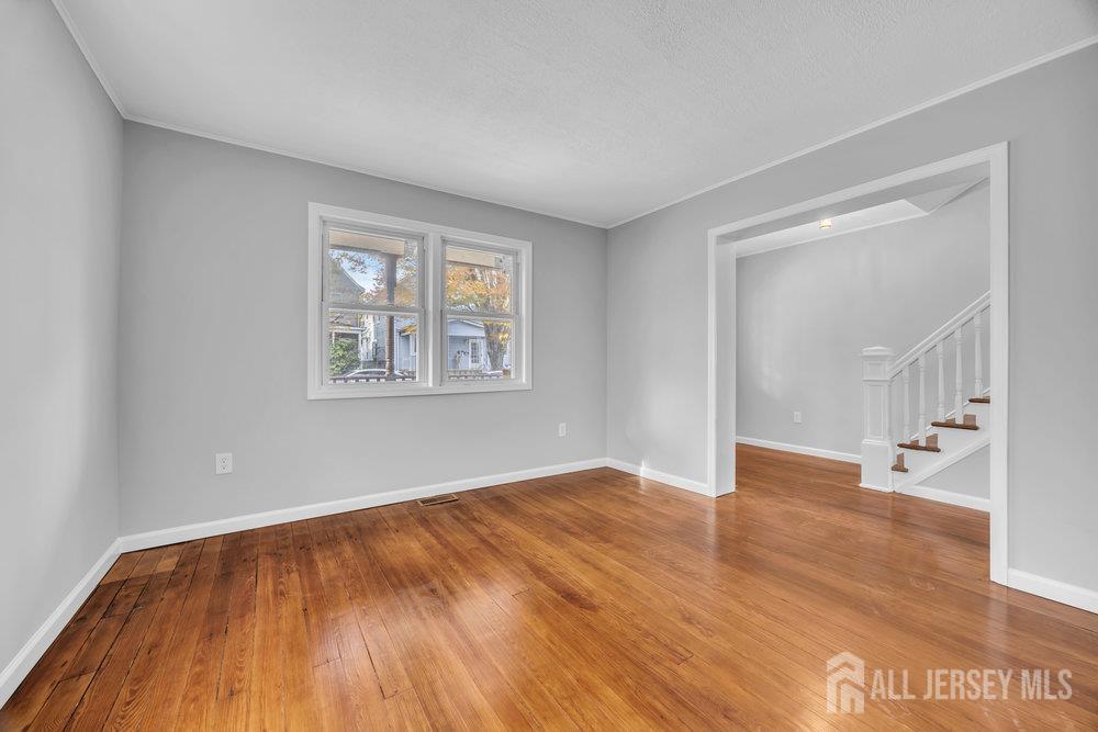49 Comstock Street New Brunswick, NJ 08901 - Photo 6 of 20 a view of empty room with wooden floor and fan
