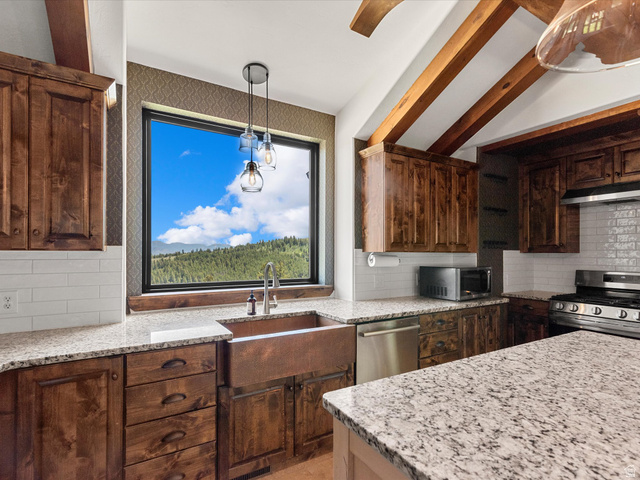 1225 Old Oregon Road Soda Springs, ID 83276 - Photo 13 of 67 Kitchen featuring a large picture window, wood-finish cabinetry, granite countertops, a copper farmhouse sink, and exposed wood beams
