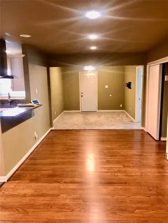 a view of a kitchen with kitchen island a sink wooden floor and a large window