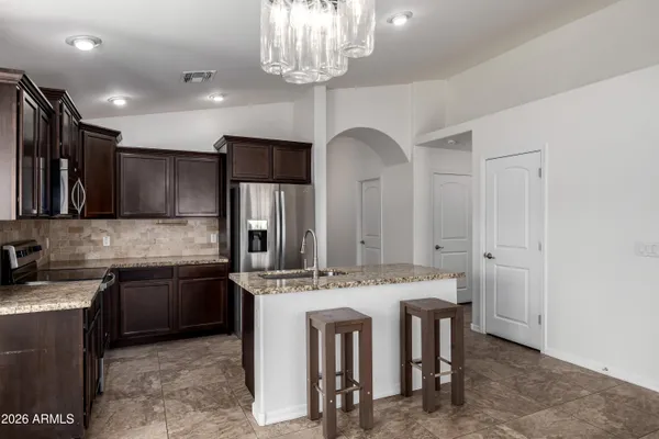 a kitchen with stainless steel appliances granite countertop a sink a stove a refrigerator cabinets and a dining table