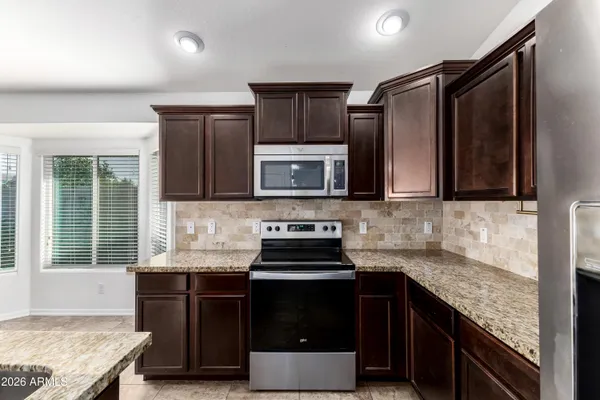 a kitchen with granite countertop stainless steel appliances a stove sink and microwave