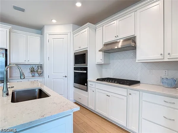 a kitchen with granite countertop a sink a stove and cabinets