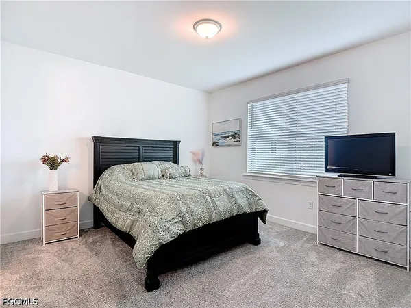 a spacious bedroom with a bed and a flat screen tv
