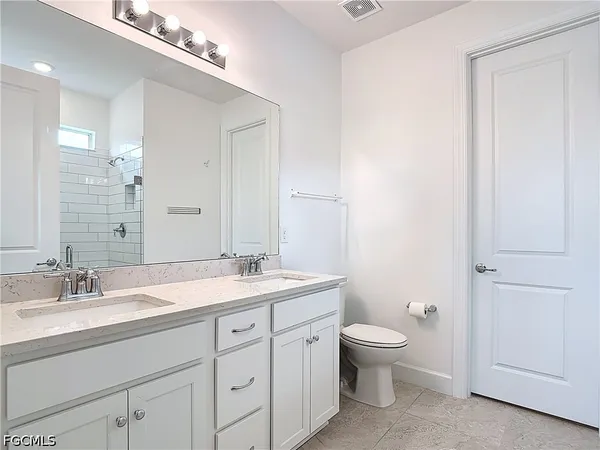 a spacious bathroom with a granite countertop sink a toilet and a mirror