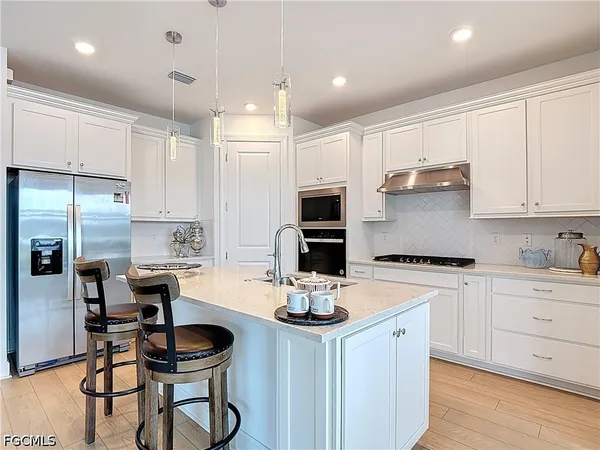 a kitchen with a refrigerator a stove cabinets and chairs with wooden floor