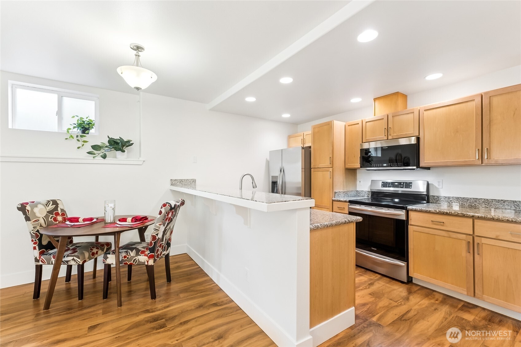 5907 40th Avenue Southwest, Unit B Seattle, WA 98136 - Photo 6 of 23 a kitchen with stainless steel appliances granite countertop a stove top oven a sink dishwasher a dining table and chairs with wooden floor