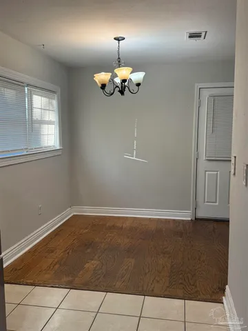 an empty room with windows and chandelier fan