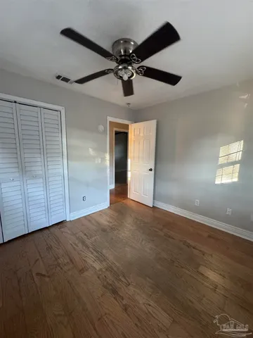an empty room with wooden floor closet and windows