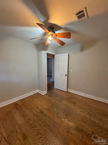 an empty room with windows and fan