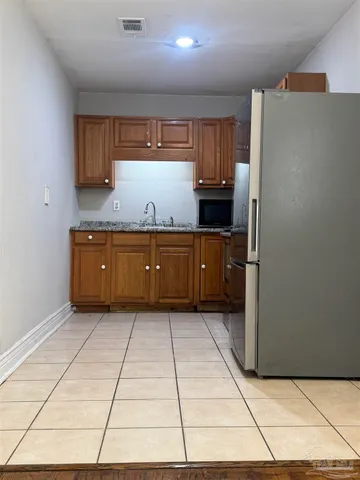 a kitchen with granite countertop a refrigerator and a stove top oven