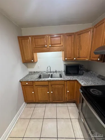 a kitchen with granite countertop a sink a stove top oven and cabinets