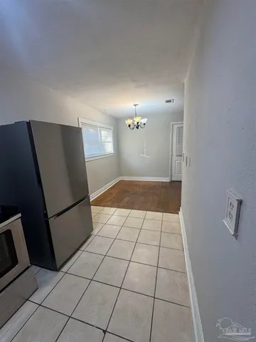 a view of a refrigerator in kitchen and an empty room